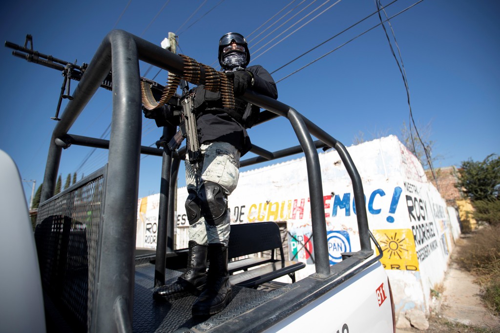 A member of the National Guard keeps watch on the bed of a truck at a crime scene where assailants left 10 bodies of men hanging from a bridge, in Ciudad Cuauhtemoc, in Zacatecas state, Mexico November 18, 2021. 