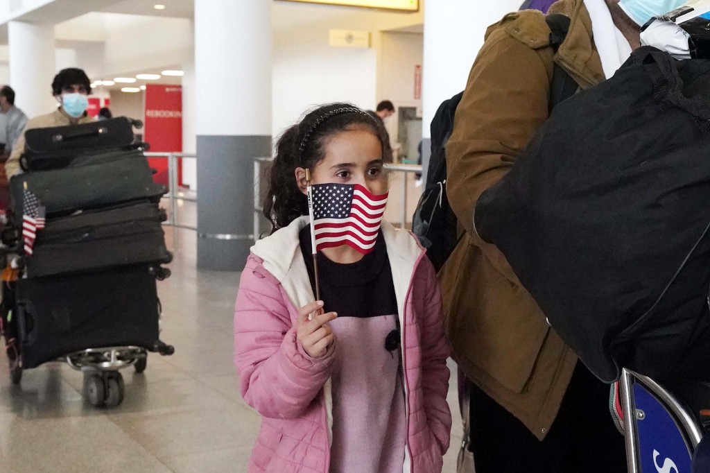 Girl holds American flag in JFK Airport.